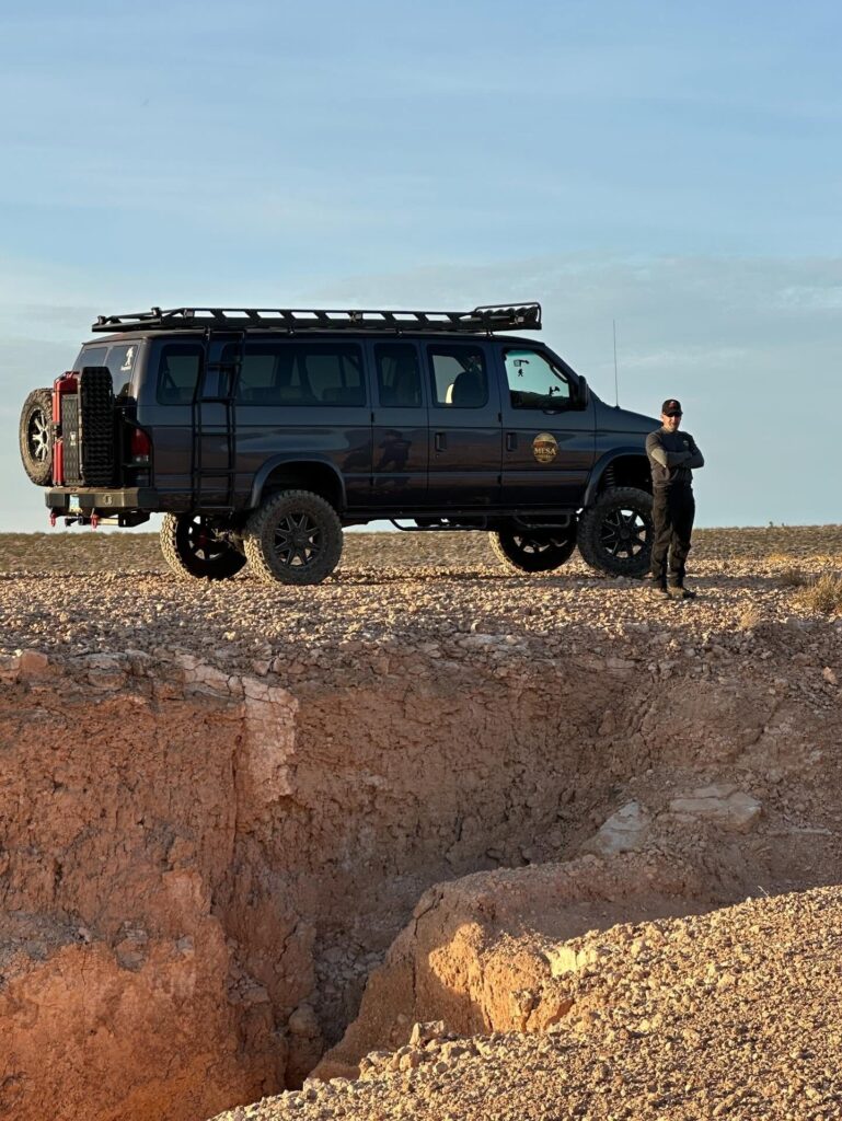 JB, owner and guide of Mesquite Mesa Tours, beside the tour van on the edge of a desert mesa