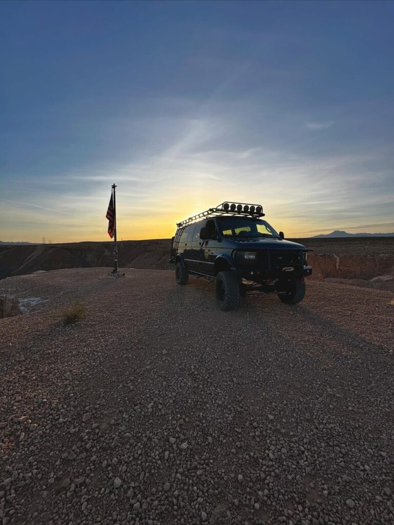 Mesquite Mesa Tours van beside an American flag at sunset on the mesa